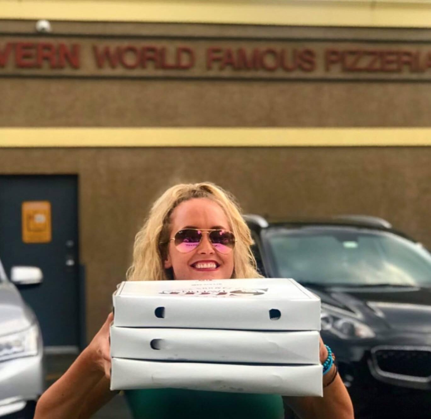 A woman carrying three world famous Star Tavern thin crust pies to go